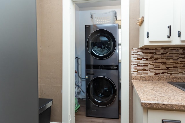 washroom featuring laundry area, wood finished floors, a textured wall, and stacked washing maching and dryer