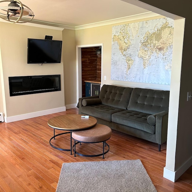 living room featuring hardwood / wood-style flooring, a baseboard radiator, a notable chandelier, and ornamental molding