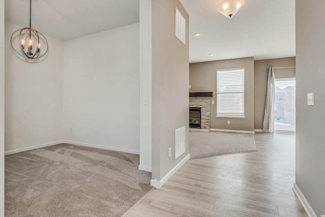 interior space featuring a fireplace, light wood-type flooring, and a notable chandelier