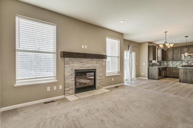 unfurnished living room featuring a notable chandelier, light colored carpet, and a fireplace