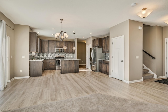 kitchen with light hardwood / wood-style floors, stainless steel appliances, hanging light fixtures, a kitchen island, and sink