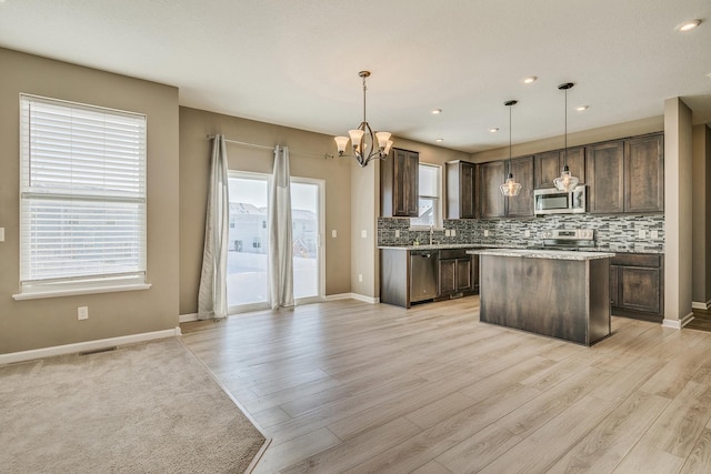 kitchen with decorative light fixtures, stainless steel appliances, dark brown cabinets, and a center island