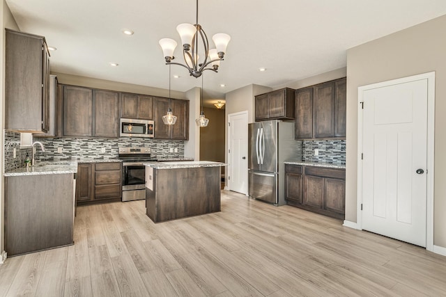 kitchen featuring stainless steel appliances, a center island, dark brown cabinetry, and hanging light fixtures