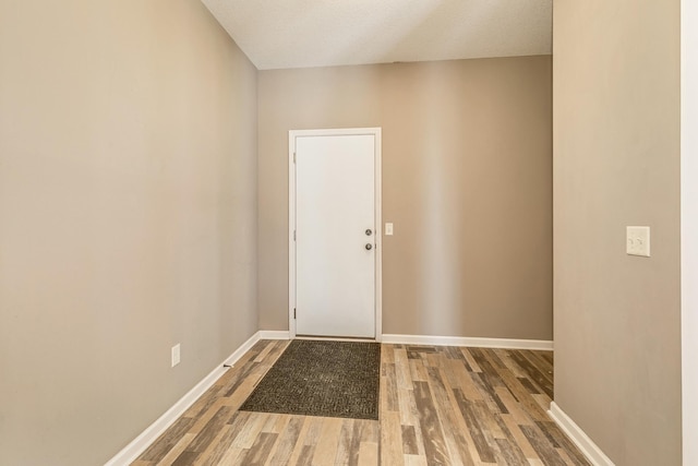 doorway to outside with a textured ceiling and wood-type flooring