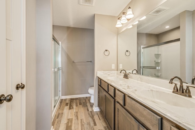 bathroom featuring toilet, hardwood / wood-style flooring, walk in shower, and vanity