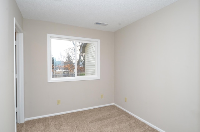 carpeted empty room featuring a textured ceiling