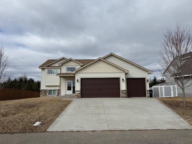 view of front of house featuring a garage, stone siding, fence, and concrete driveway