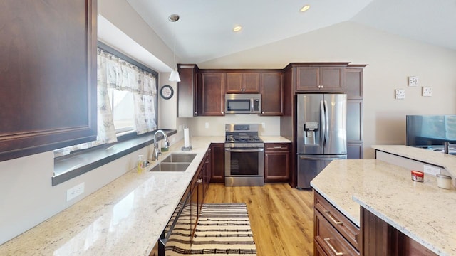 kitchen with light stone counters, pendant lighting, appliances with stainless steel finishes, vaulted ceiling, and a sink