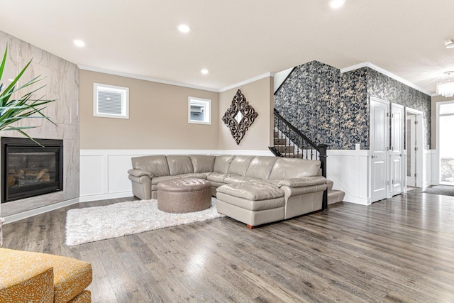 living room featuring hardwood / wood-style floors, plenty of natural light, ornamental molding, and a tile fireplace