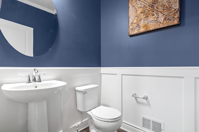 bathroom featuring toilet, ornamental molding, and sink