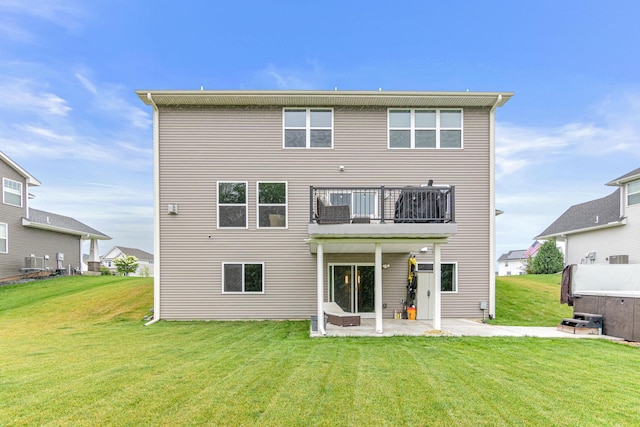 rear view of property featuring a yard, a patio area, and a balcony