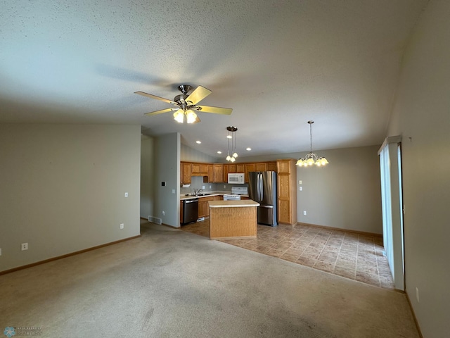 kitchen with appliances with stainless steel finishes, decorative light fixtures, lofted ceiling, a kitchen island, and ceiling fan with notable chandelier