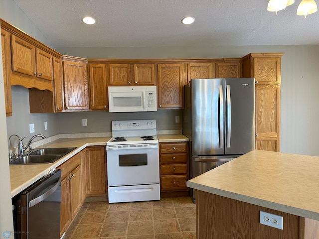 kitchen with a textured ceiling, appliances with stainless steel finishes, and sink