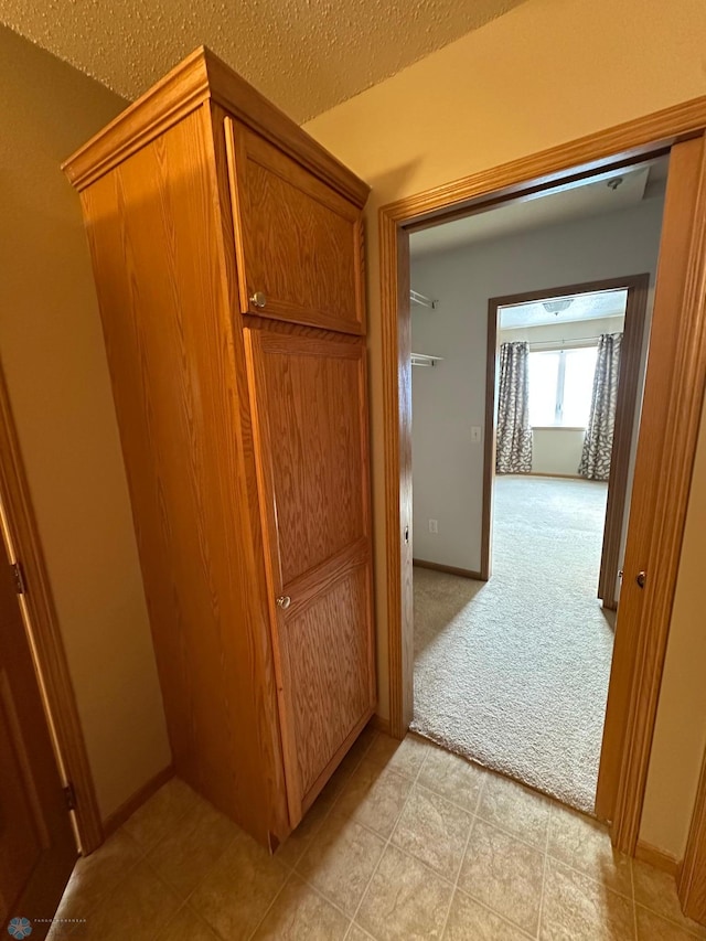 hallway featuring light carpet and a textured ceiling