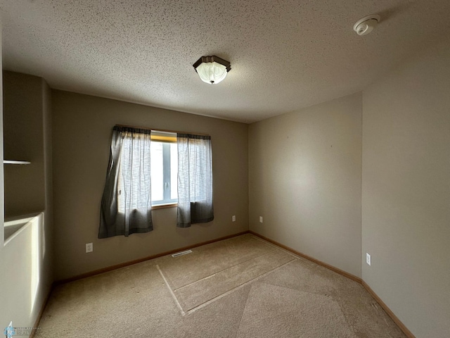 empty room featuring a textured ceiling and light carpet