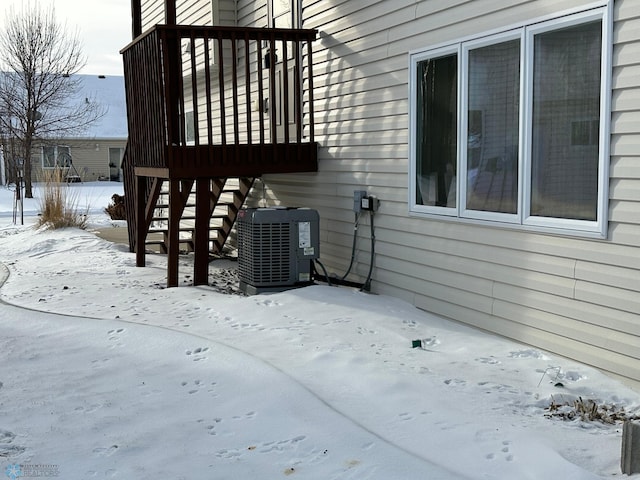 snow covered property with central air condition unit