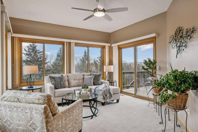 living room featuring light carpet, ceiling fan, a wealth of natural light, and a textured ceiling