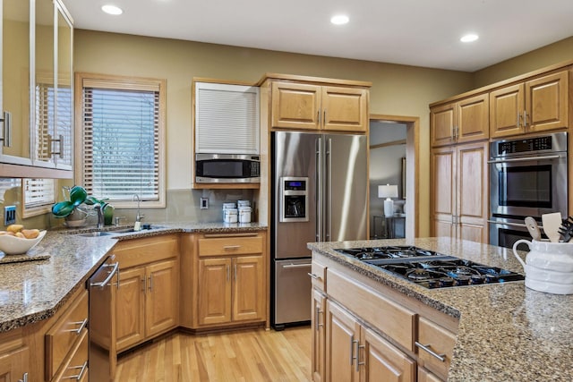 kitchen featuring sink, backsplash, light stone countertops, light hardwood / wood-style floors, and stainless steel appliances