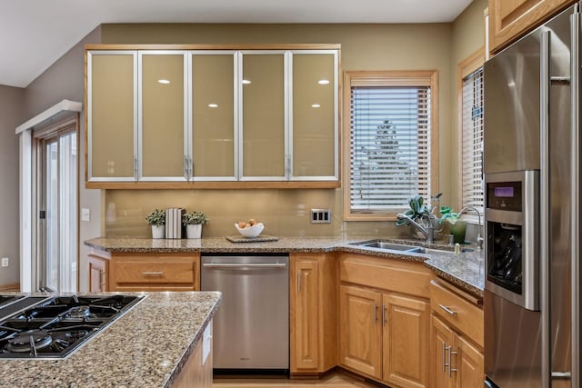 kitchen featuring sink, light stone counters, and appliances with stainless steel finishes