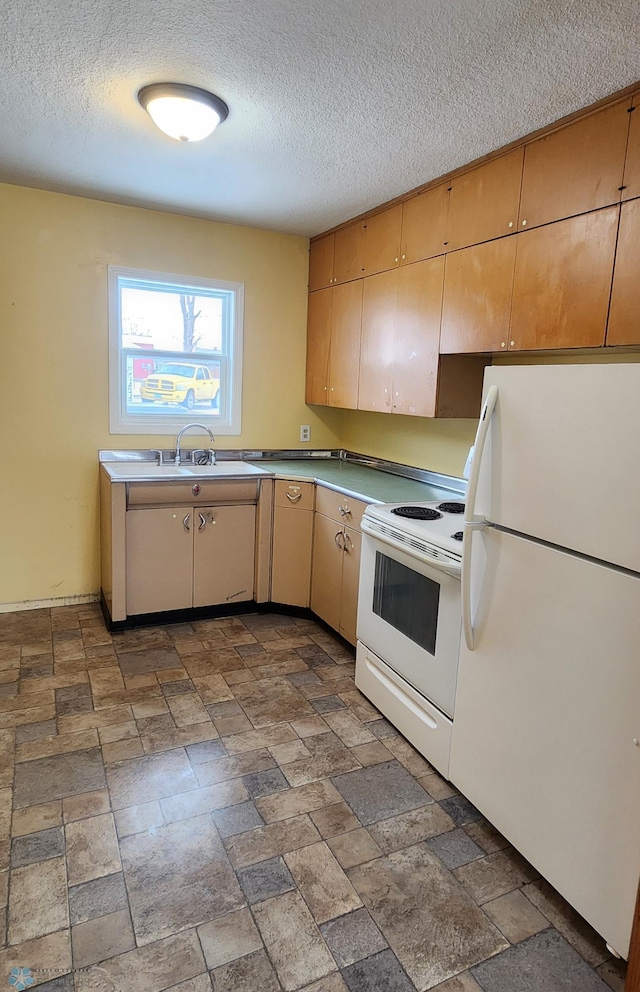 kitchen with a textured ceiling, white appliances, and sink