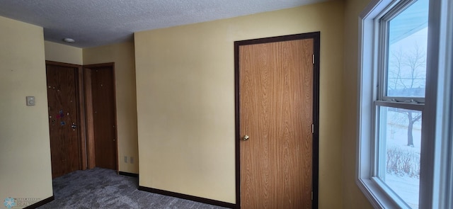 unfurnished room with a textured ceiling and dark colored carpet