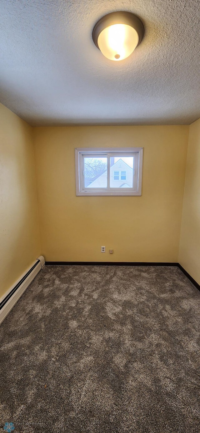 spare room with dark carpet, baseboard heating, and a textured ceiling