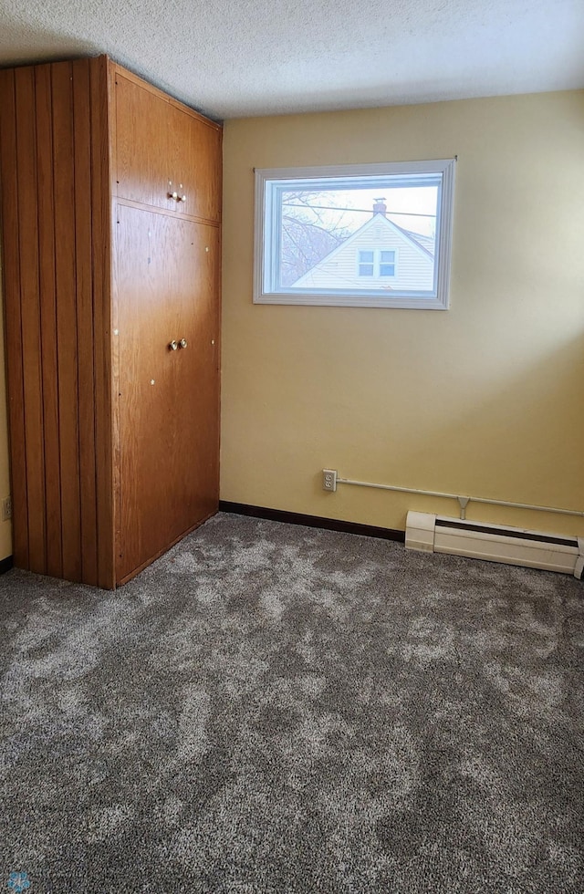 carpeted spare room featuring a textured ceiling and baseboard heating