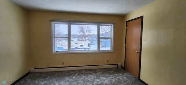 empty room with a textured ceiling, dark carpet, and a baseboard heating unit