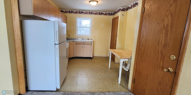 kitchen with a textured ceiling, white fridge, and sink