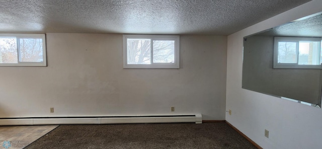 spare room featuring a textured ceiling, plenty of natural light, and a baseboard heating unit