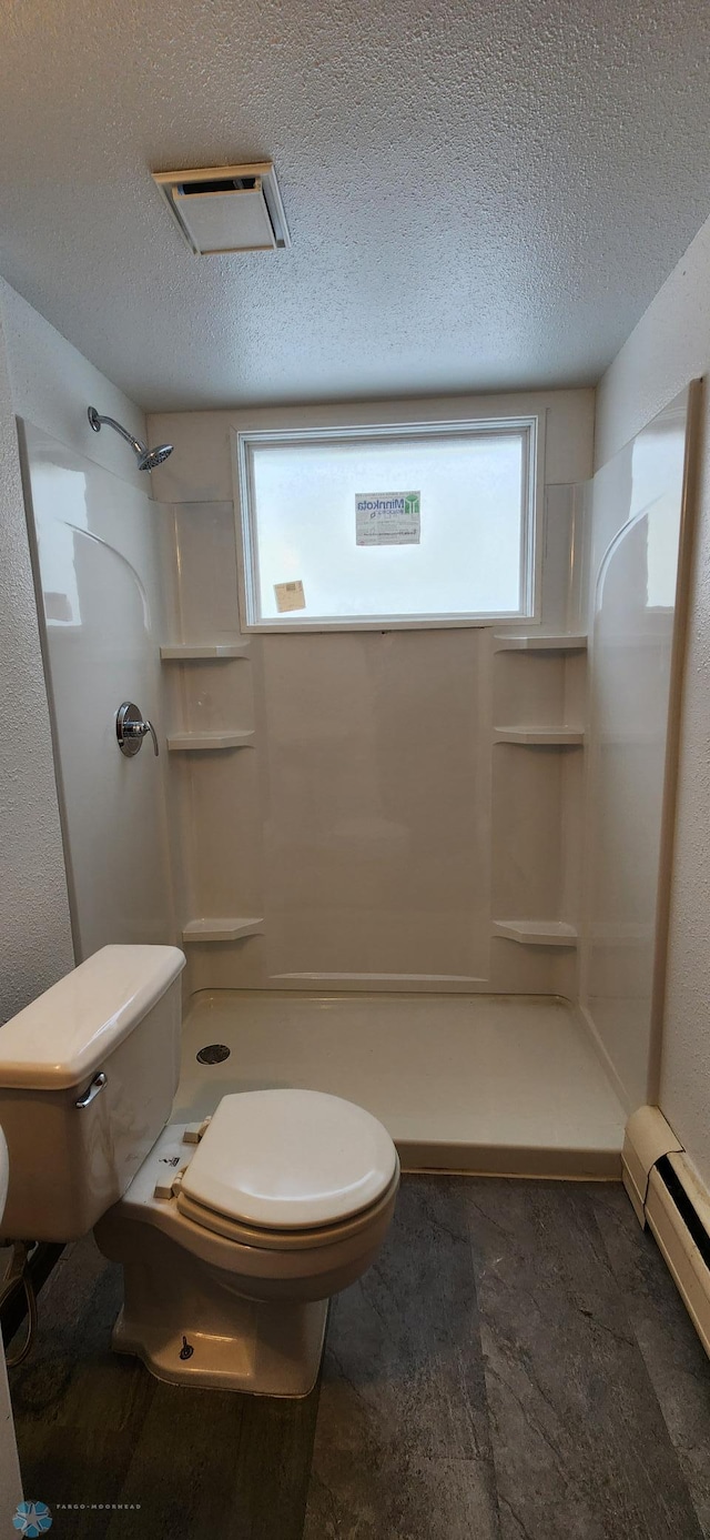 bathroom with plenty of natural light, a textured ceiling, and a baseboard radiator