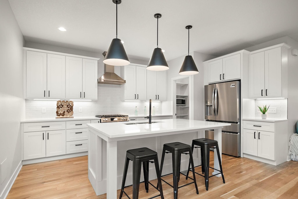 kitchen with white cabinets, appliances with stainless steel finishes, tasteful backsplash, an island with sink, and sink