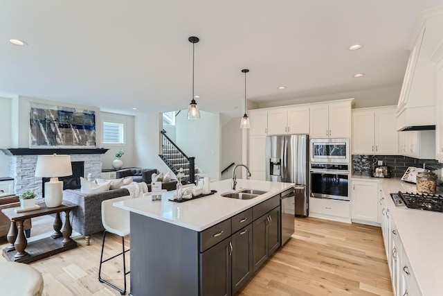 kitchen featuring white cabinetry, sink, hanging light fixtures, a center island with sink, and appliances with stainless steel finishes