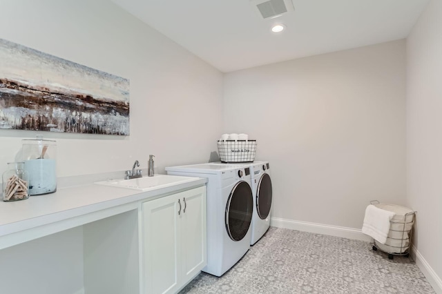 clothes washing area with washing machine and clothes dryer, sink, and cabinets