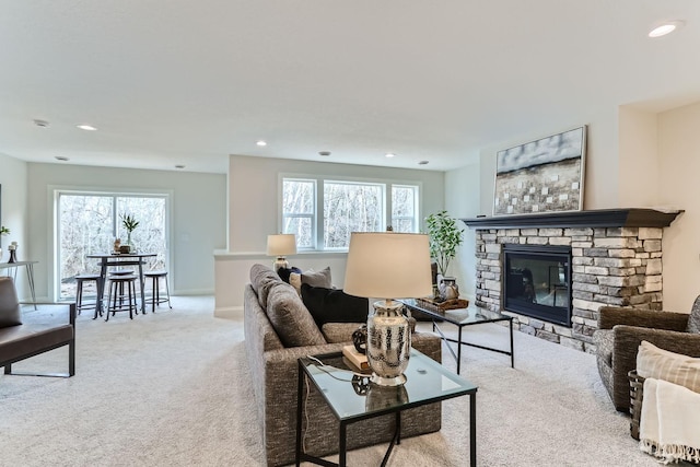 living room with a stone fireplace, light colored carpet, and a healthy amount of sunlight