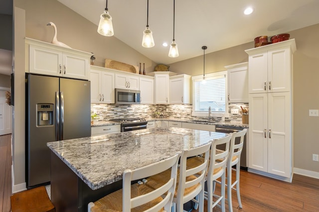 kitchen with pendant lighting, white cabinets, sink, a kitchen island, and stainless steel appliances