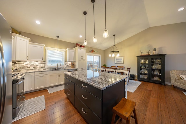 kitchen featuring backsplash, a kitchen island, decorative light fixtures, white cabinetry, and lofted ceiling