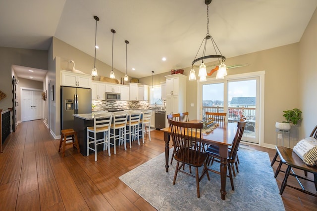 dining space featuring hardwood / wood-style flooring, a notable chandelier, and vaulted ceiling