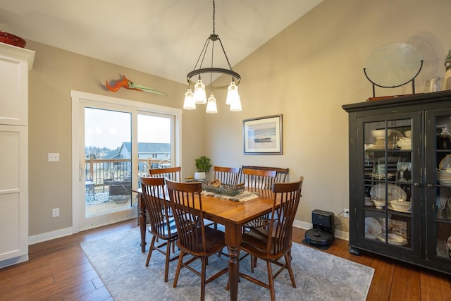 dining room featuring dark hardwood / wood-style floors, an inviting chandelier, and lofted ceiling