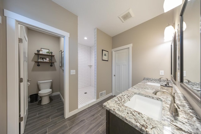 bathroom with tiled shower, vanity, and toilet