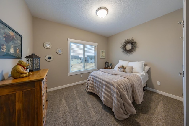 bedroom featuring dark colored carpet and a textured ceiling