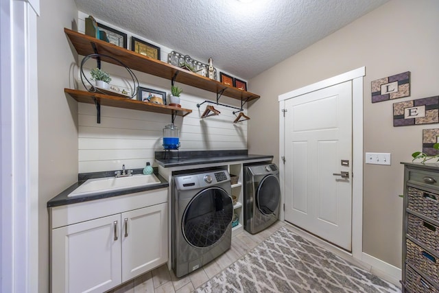 laundry area featuring sink, cabinets, a textured ceiling, washer and dryer, and light wood-type flooring