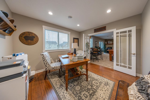 home office with a fireplace, french doors, and wood-type flooring