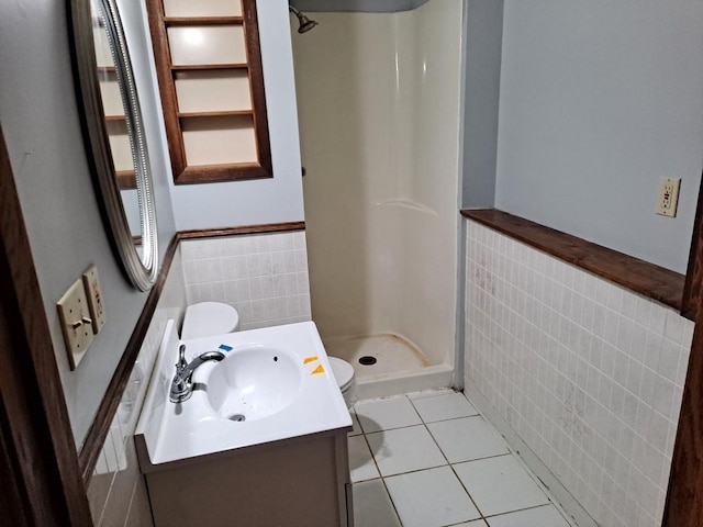 bathroom featuring vanity, tile patterned flooring, toilet, tile walls, and walk in shower