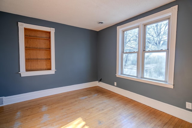 spare room with wood-type flooring and built in features