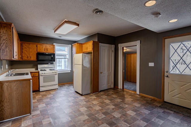 kitchen with a textured ceiling, sink, and white appliances