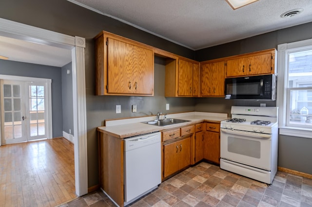 kitchen with a healthy amount of sunlight, white appliances, sink, and french doors