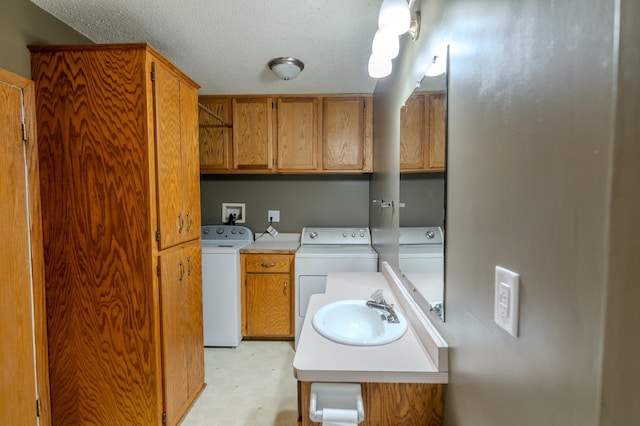 laundry room featuring cabinets, washing machine and dryer, sink, and a textured ceiling