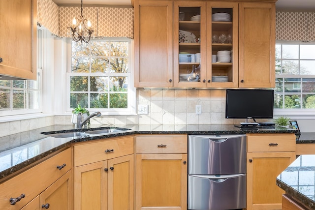 kitchen with refrigerator, a notable chandelier, sink, dark stone counters, and pendant lighting