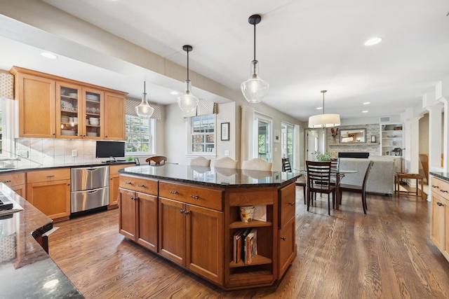 kitchen featuring dark stone countertops, a kitchen island, dark hardwood / wood-style floors, decorative light fixtures, and tasteful backsplash